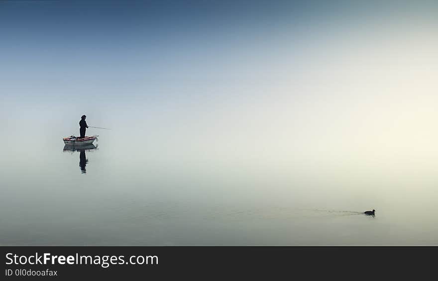 Person on White Boat Fishing on Body of Water