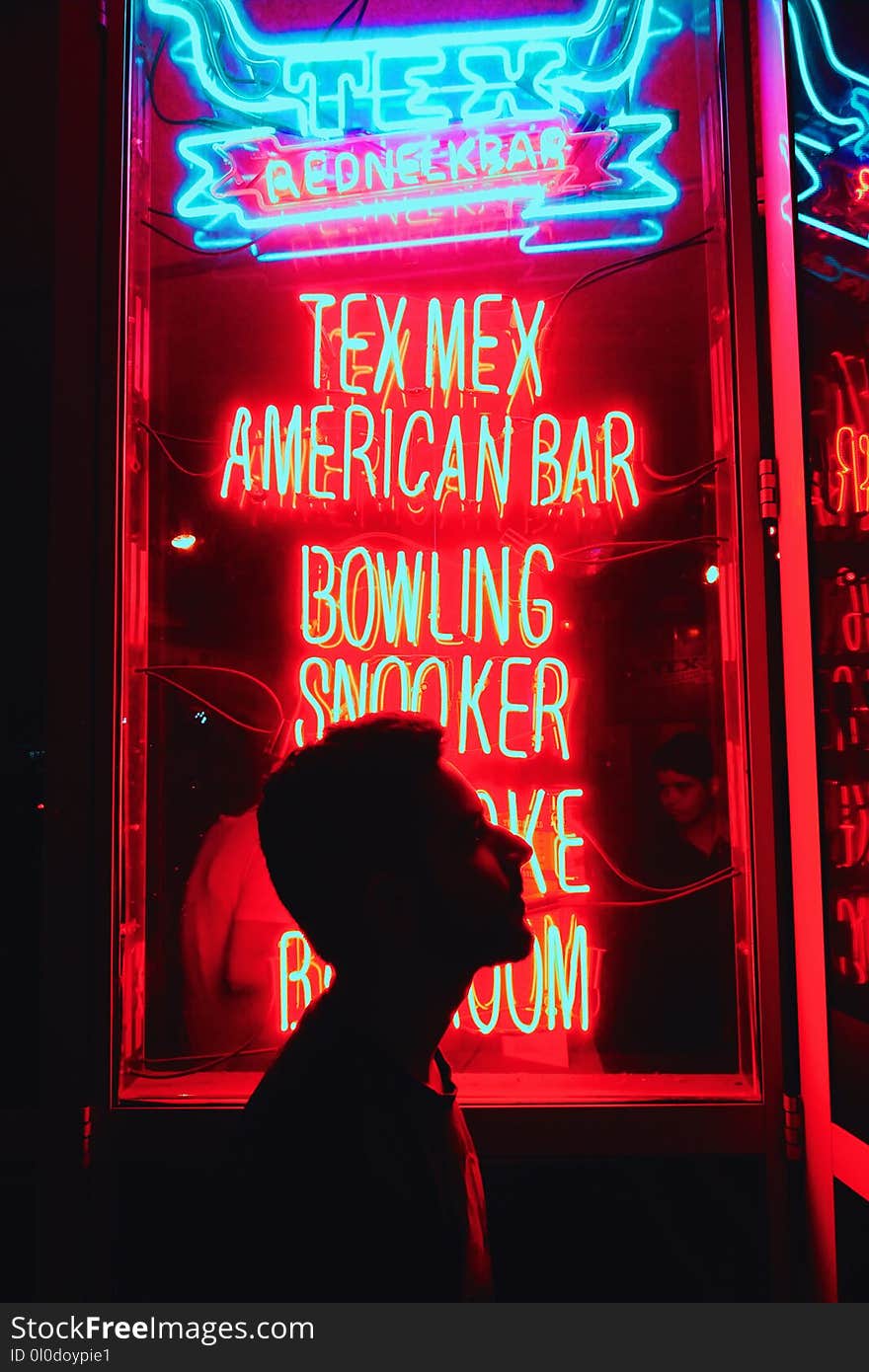 Silhouette of Man in Front of Red and Blue Led Light Signage