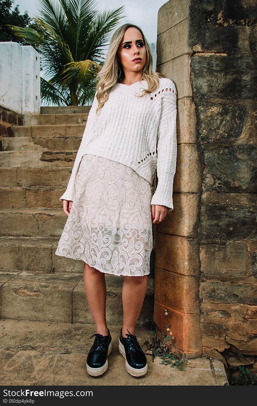 Woman in White Knitted Top Leaning of Wall