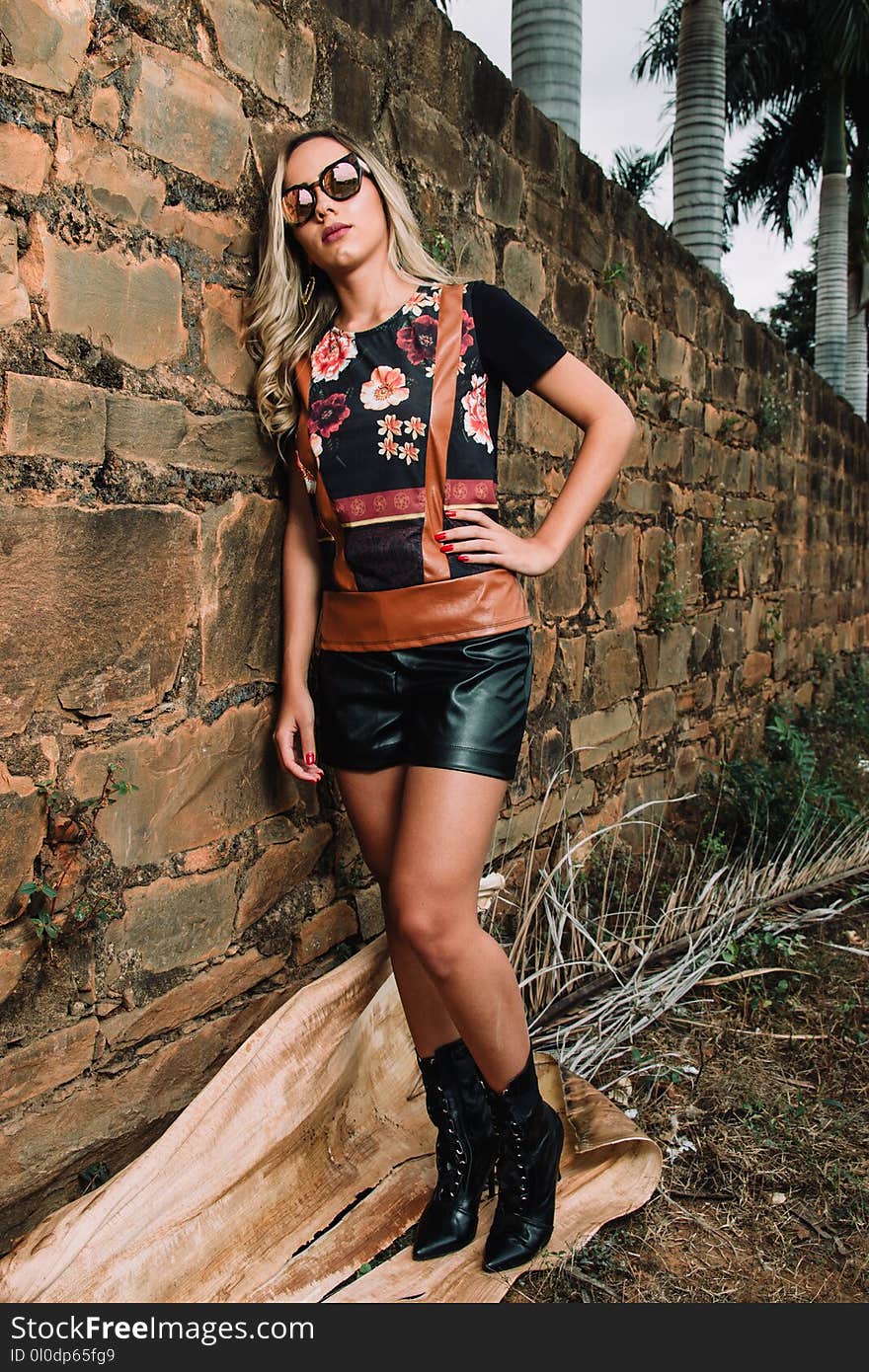 Woman Wearing Black and Red Floral Print Crew-neck Shirt Beside Brown Brick Wall