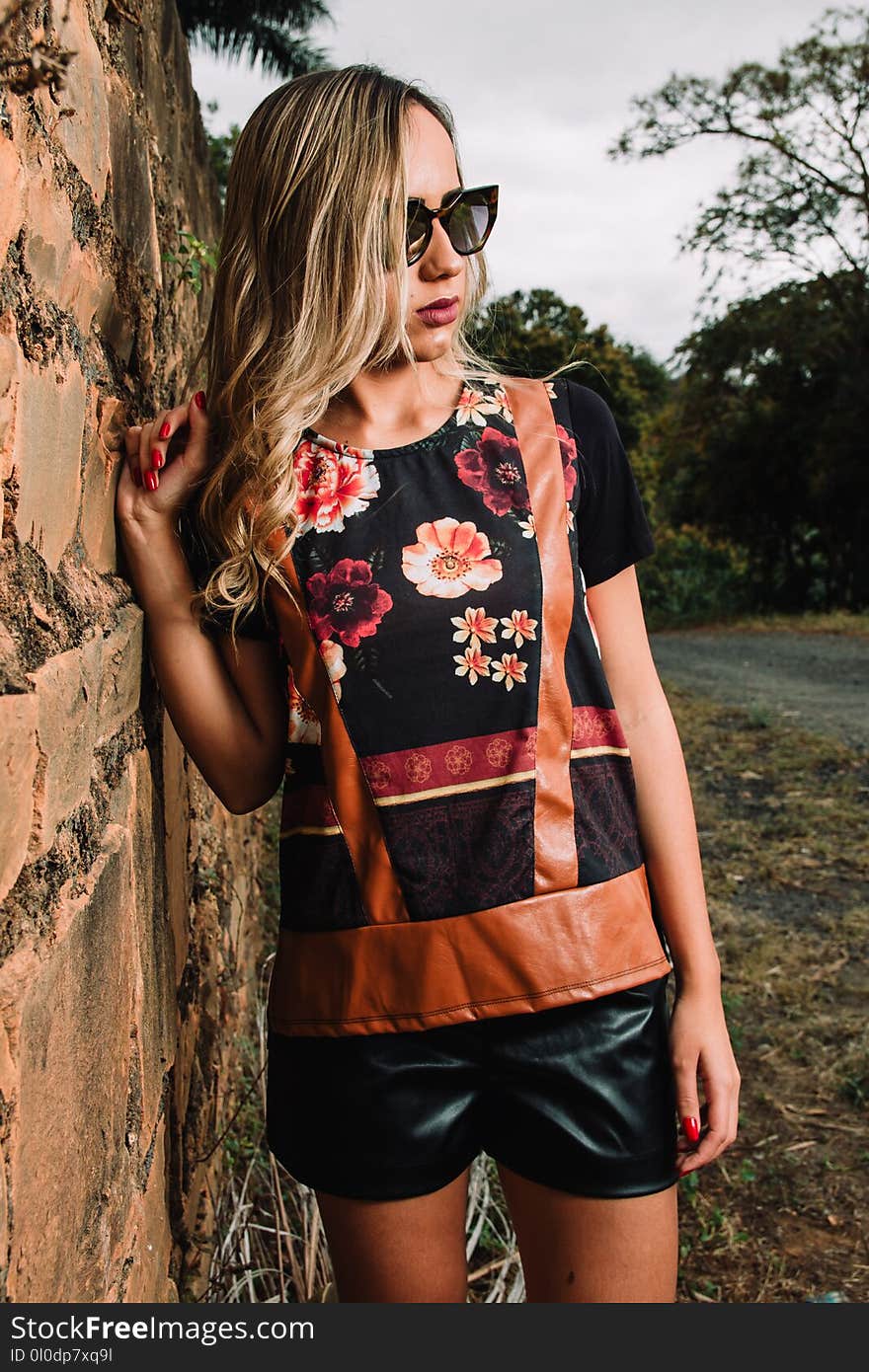 Woman Wearing Black Floral Short-sleeved Shirt and Black Pants Standing Near Wall