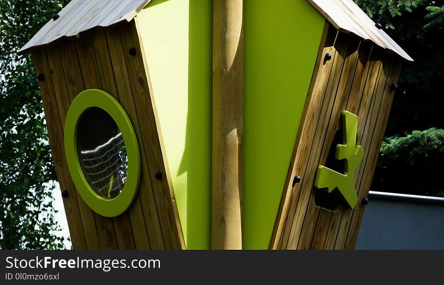 Wooden treehouse in playground with green plastic window and natural park surrounding in bright sunlight in the summer. Wooden treehouse in playground with green plastic window and natural park surrounding in bright sunlight in the summer