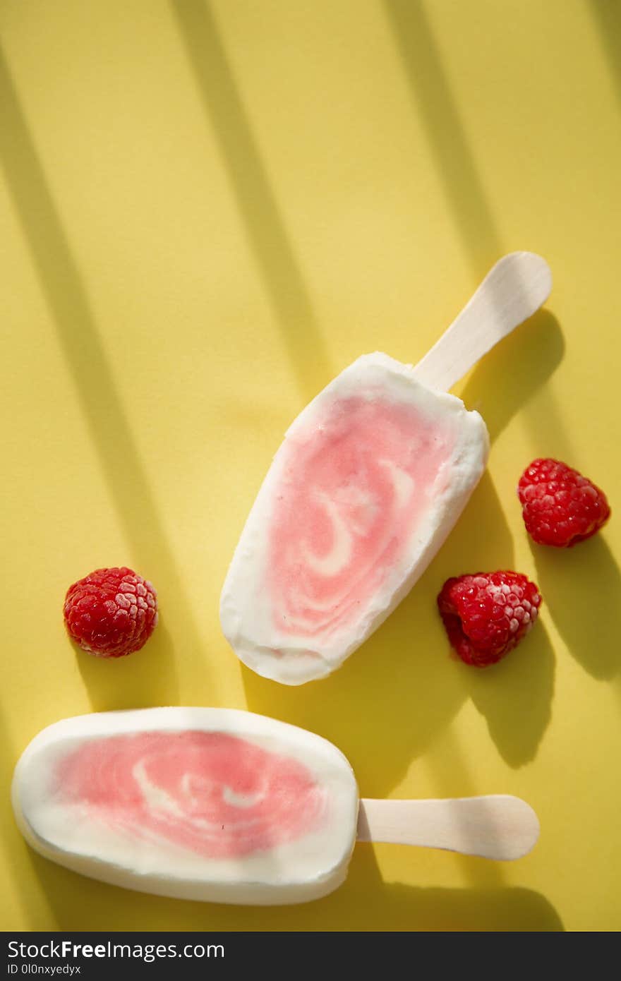 Two berry sorbet and yogurt popsicle with raspberry on a yellow background. Two berry sorbet and yogurt popsicle with raspberry on a yellow background