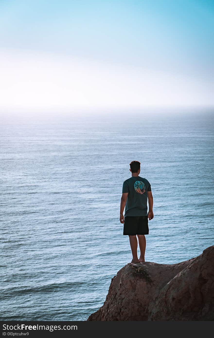 Man Standing on Cliff Near Sea