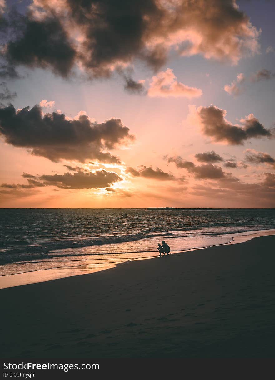 Silhouette of Two Person at Seashore during Sunset