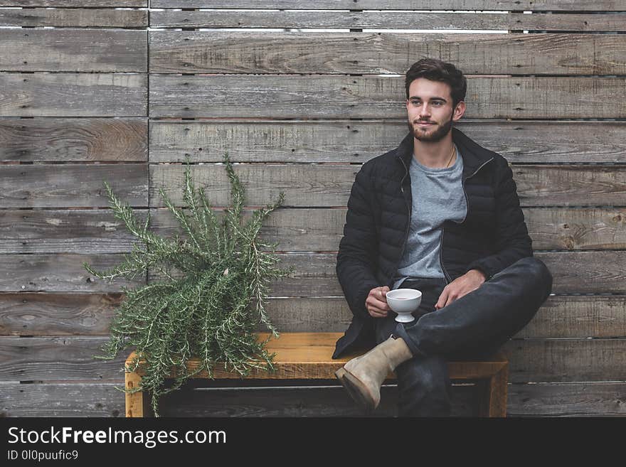 Man Sitting on Bench Having a Cup of Coffee