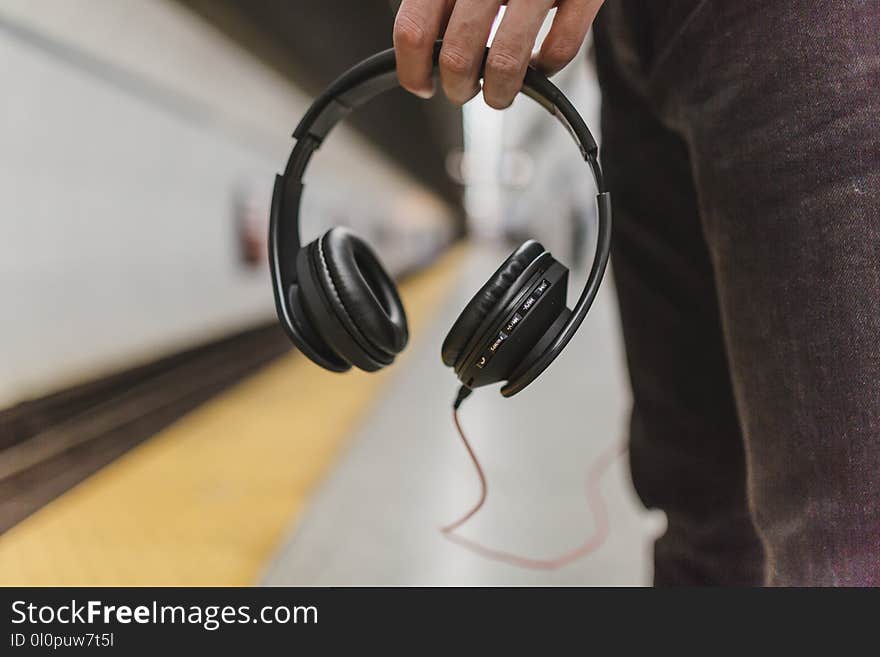 Shallow Focus Photography of Person Holding Headphones