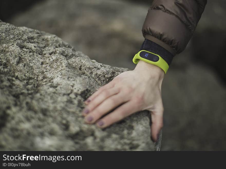 Person Wearing Yellow Fitness Band Holding Rock