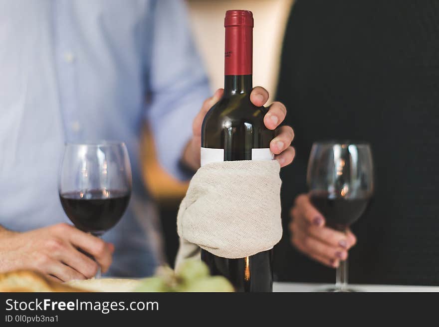 Man Holding White Labeled Red Wine Bottle Near Wine Glasses