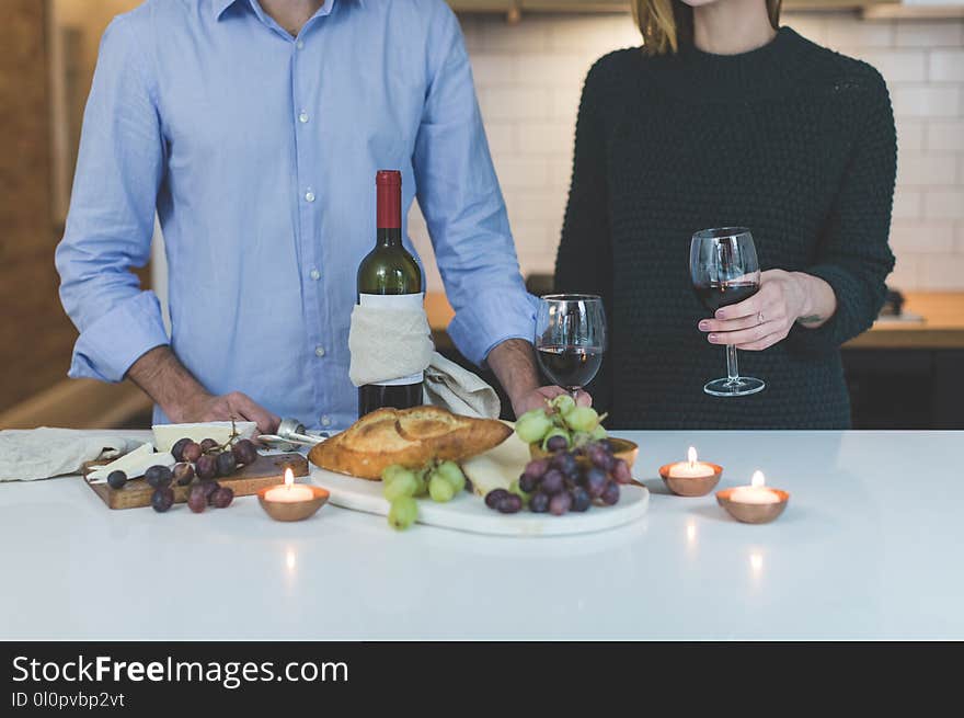 Man Standing Beside Woman in Front of White Wooden Dining Table