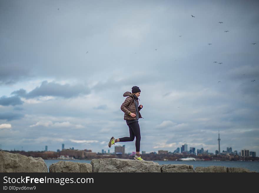 Woman Standing on Stone Near Body of Water