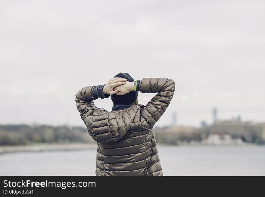 Person Holding Head Facing Body of Water