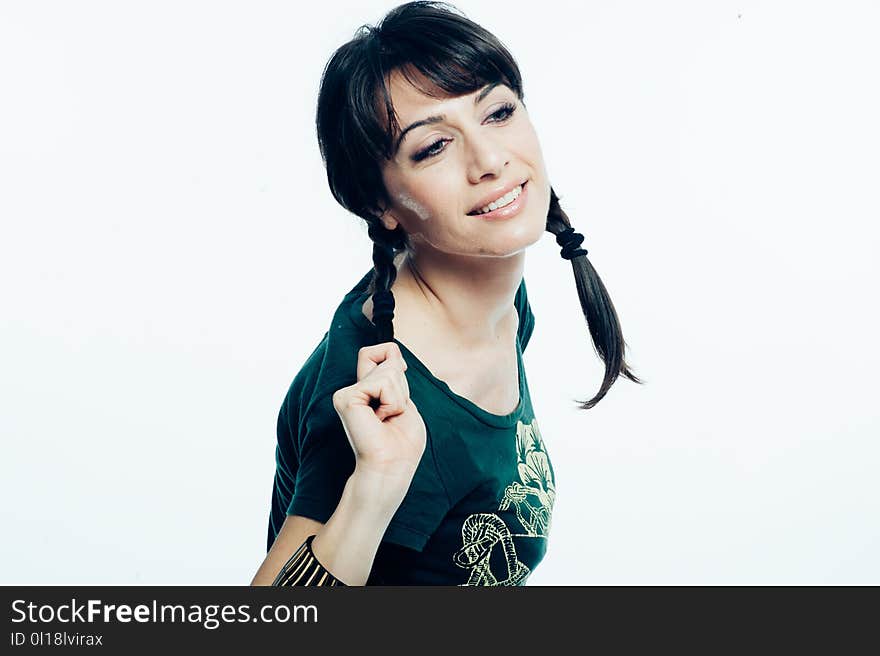 Young caucasian brunette with tail hair having fun in studio. White background, green shirt dressed. Copy space. Young caucasian brunette with tail hair having fun in studio. White background, green shirt dressed. Copy space