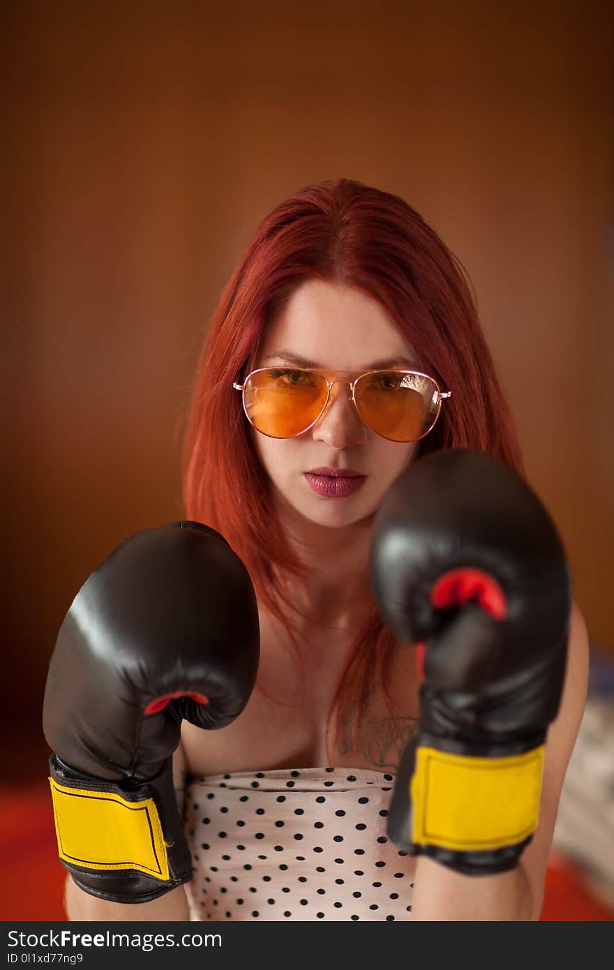 Pretty Young Woman With Red Hair, Sunglasses And Boxing Gloves Looks Upset