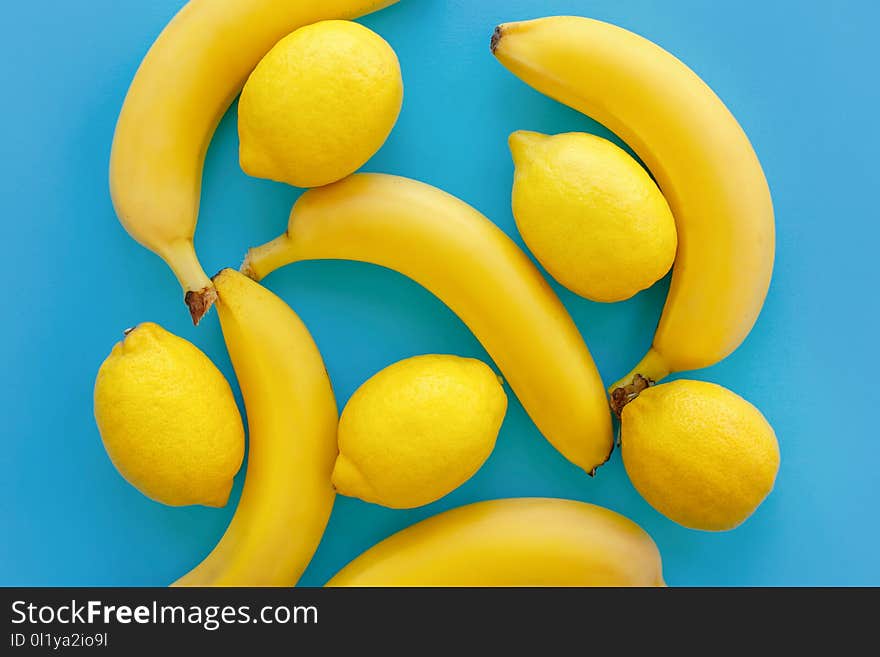 Yellow bananas and lemons on bright blue paper, trendy flat lay. fruits modern image, top view. juicy summer vitamin abstract background. pop art style. minimalism pattern