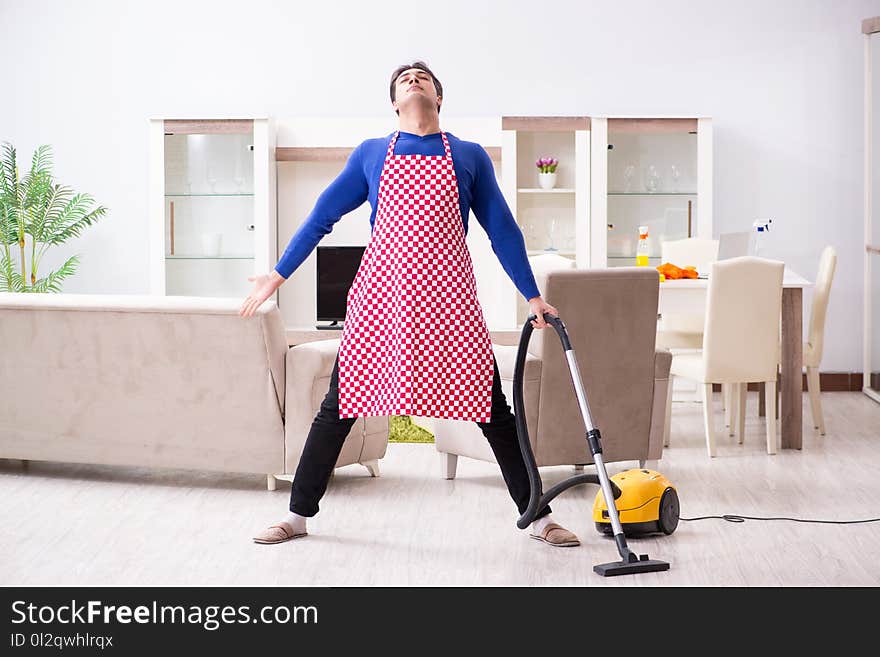 The young man vacuum cleaning his apartment