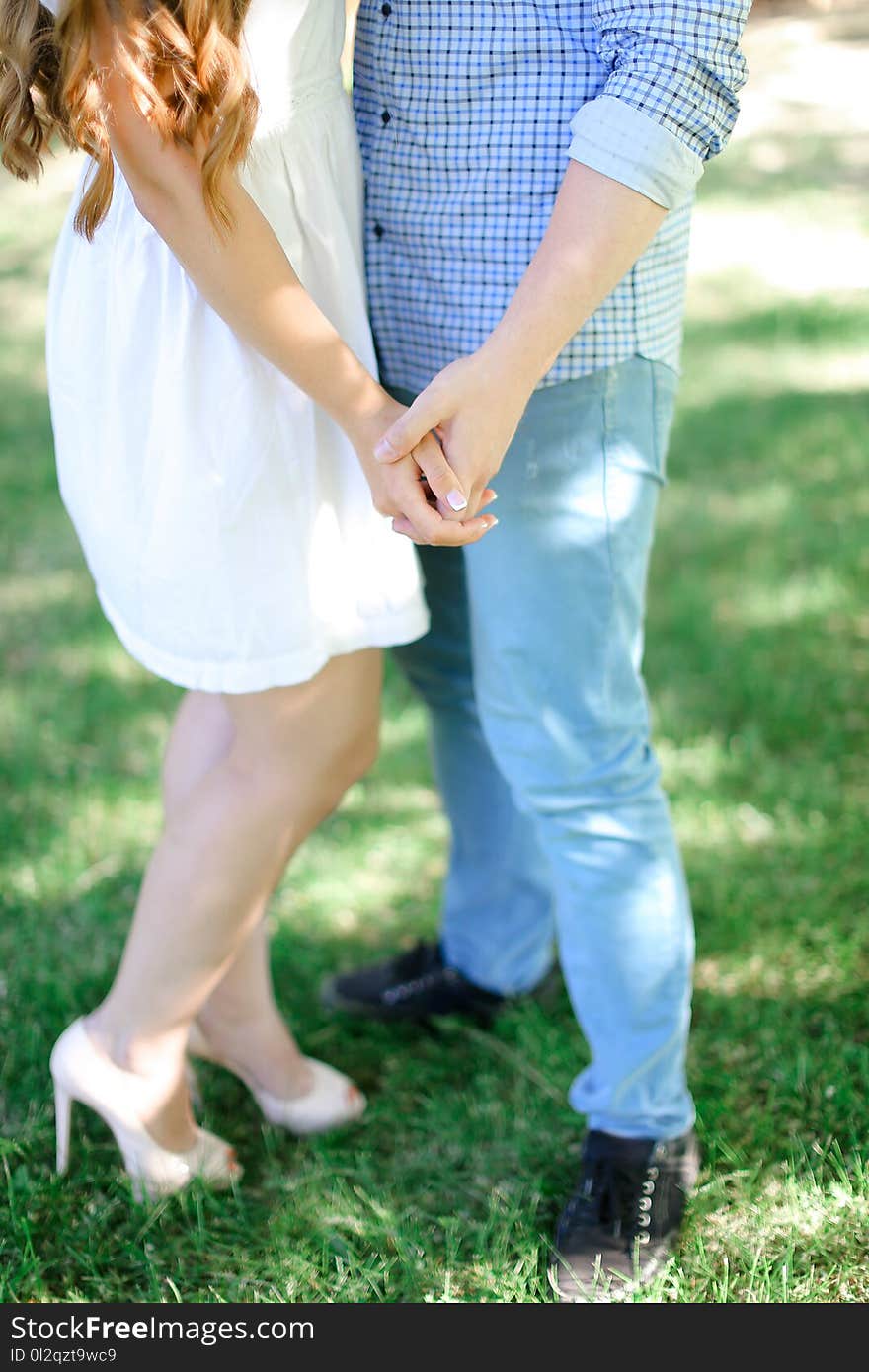 Closeup boy and girl holding hands in grass background. Concept of relationships and love.