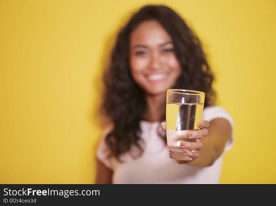 Portrait of a glass of mineral water hold by asian girl on yellow background