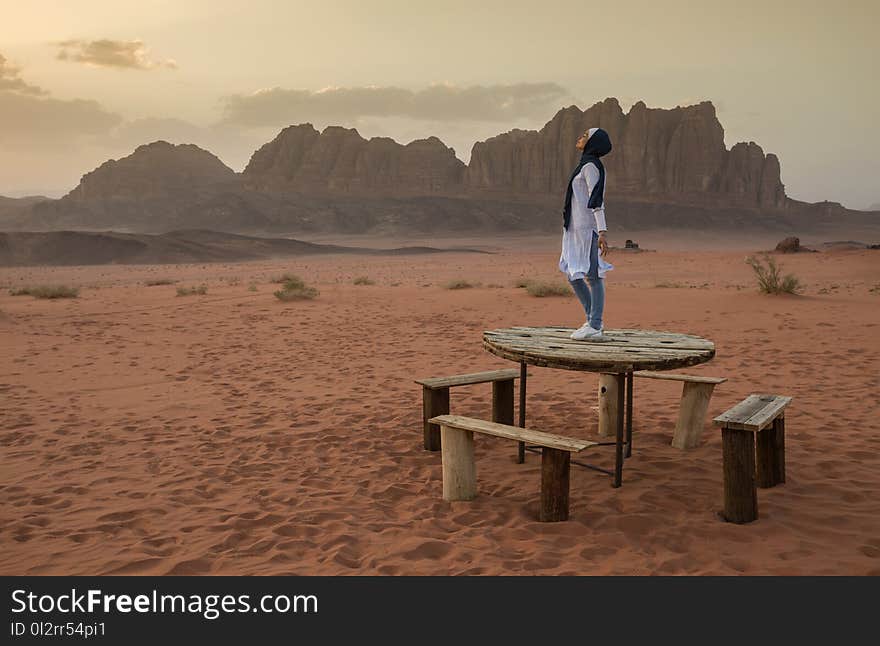 Person Stands on Brown Wooden Table