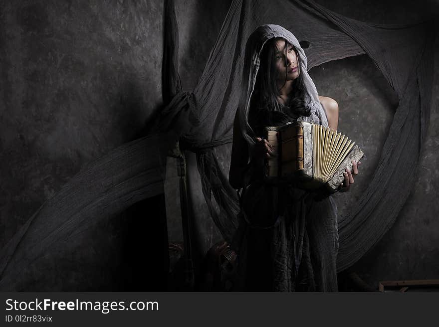 Woman Wearing Gray Scarf Holding Accordion