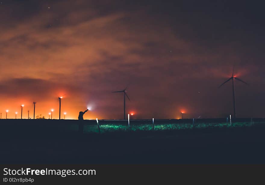 Photography of Person Holding Flashlight Near Windmills during Night Time