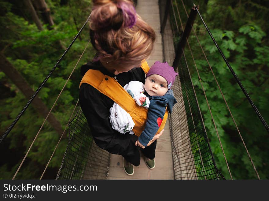 Woman Carrying Baby on Bridge