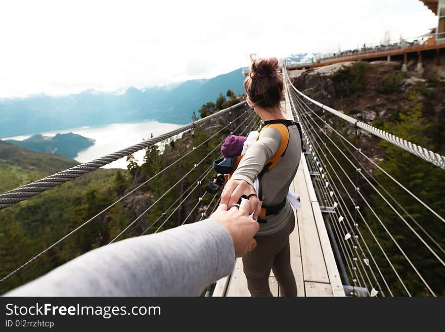 Woman With Yellow Backpack Standing on Hanging Bridge With Trees