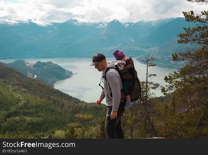 Man Carrying Baby Near Lake