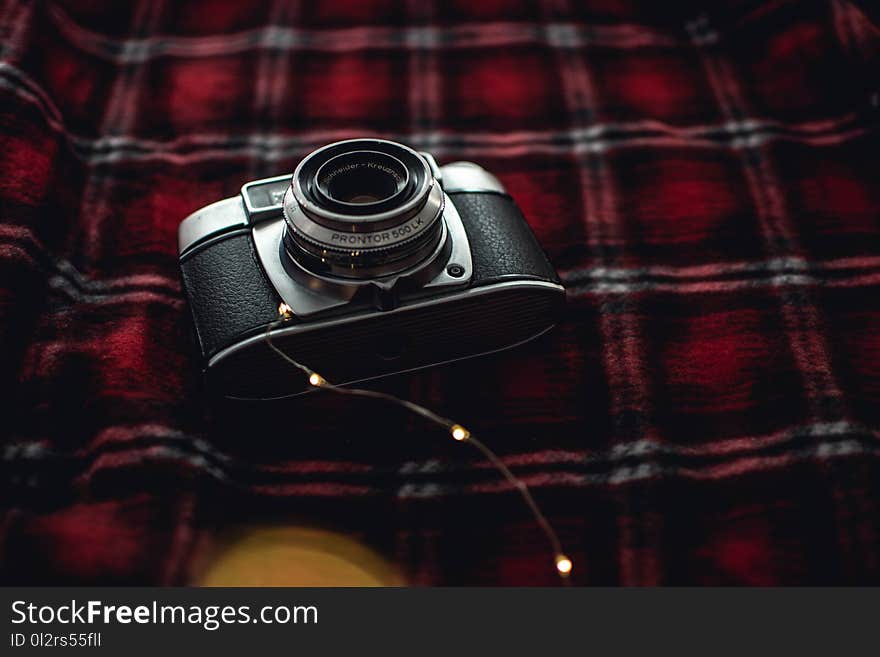 Black and Gray Point-and-shoot Camera on Red, Black, and White Plaid Textile