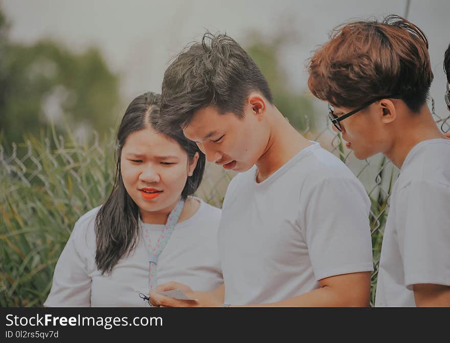 Man in White T-shirt Looking Into His Phone