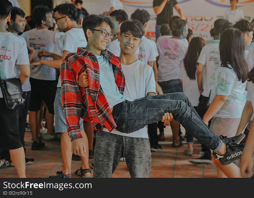 Photo of Man in White Shirt Carrying Man in Red and Gray Polo Shirt