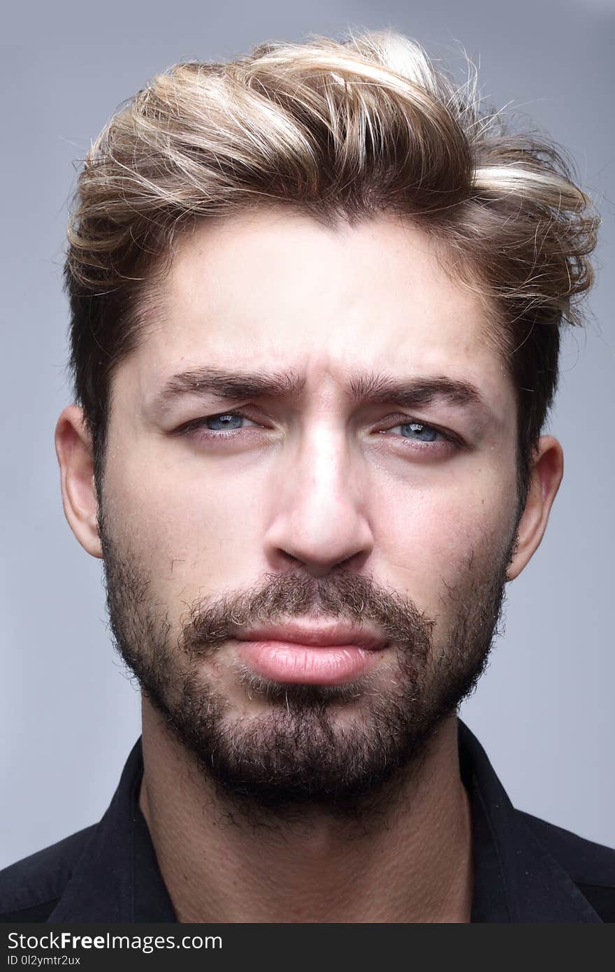 Close-up of handsome young shirtless man holding hand on chin while standing against grey background. Close-up of handsome young shirtless man holding hand on chin while standing against grey background