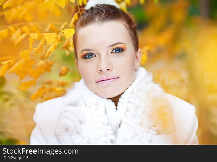 Young lady with blue eyes and red hair wearing knitted white sweater and gloves among golden leaves. Young lady with blue eyes and red hair wearing knitted white sweater and gloves among golden leaves