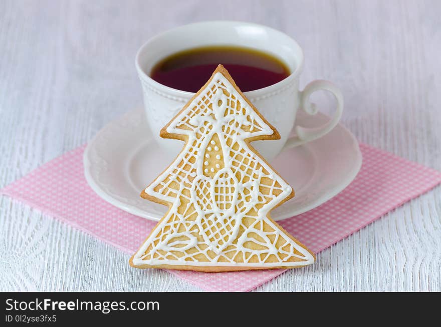 Christmas tree gingerbread with coffe cup on wooden table with pink napkin, closeup