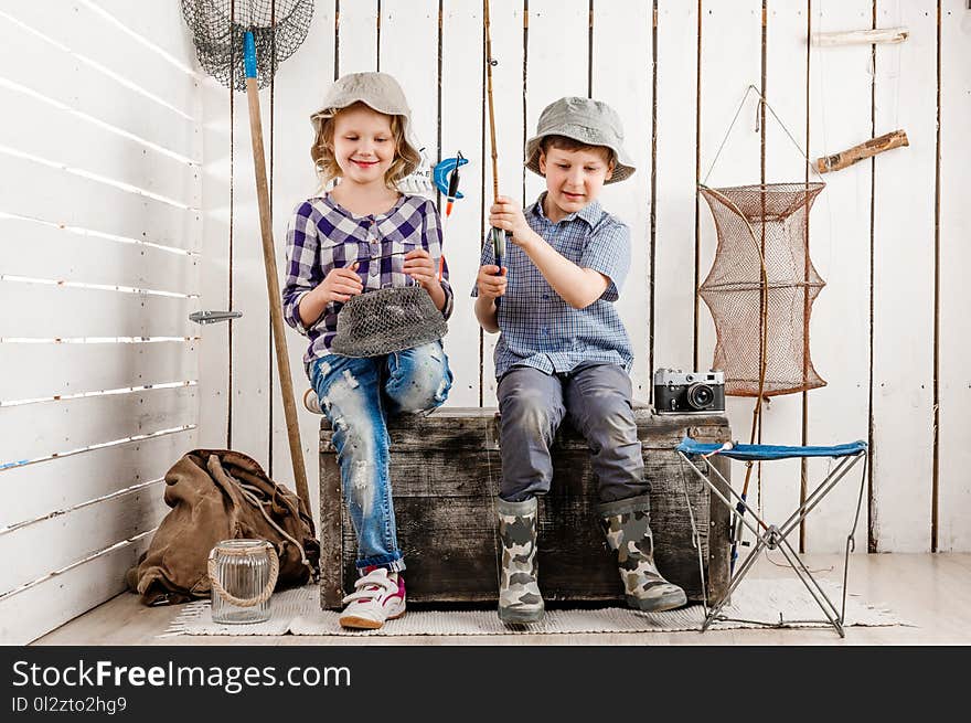 Two little children sitting on chest with net and rod in hands