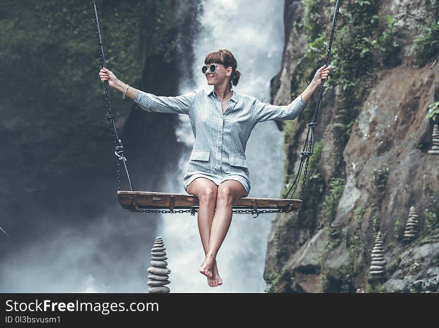 Photo of Woman Riding Swing in Front of Waterfalls