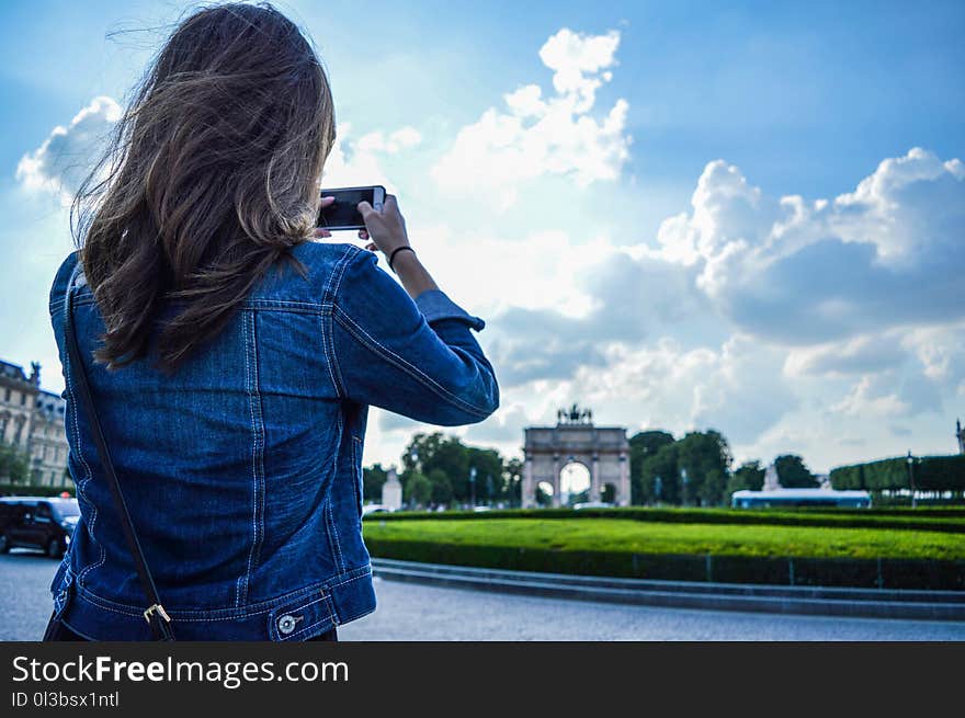 Woman Wearing Blue Denim Jacket Standing While Holding Smartphone