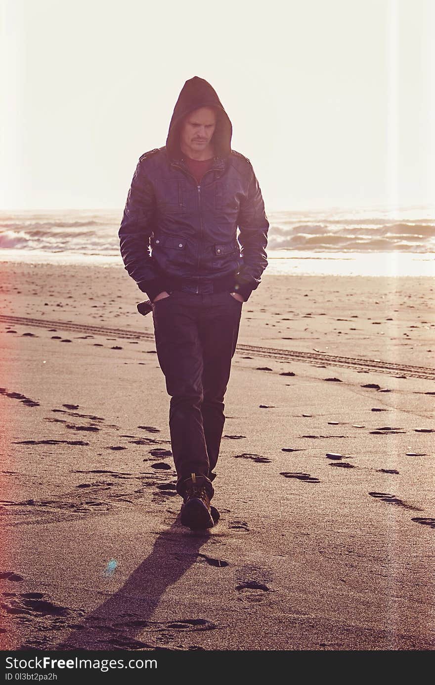 Man Walking on Beach Wearing Black Leather Coat