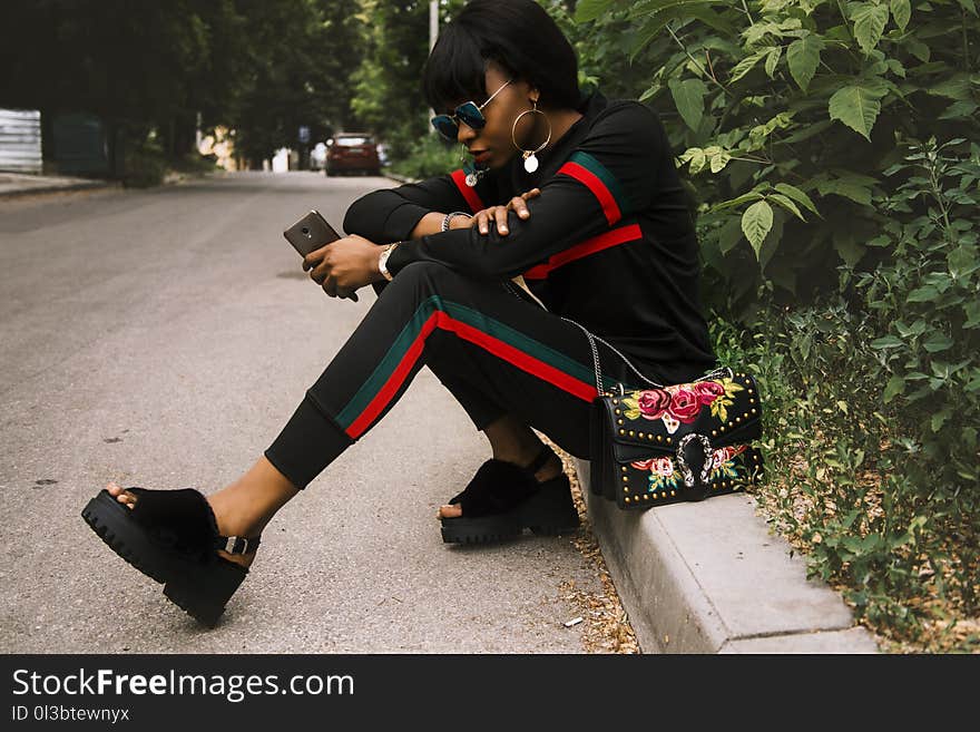 Woman Sitting on Gray Concrete Sidewalk Taken