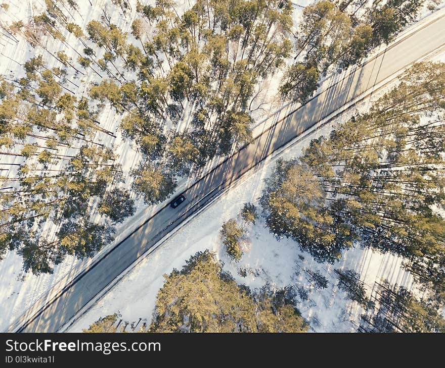 Snowy road with a moving car in winter. Aerial photography