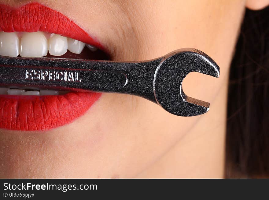 Close View of Woman With Red Lips Biting Gray Special Wrench