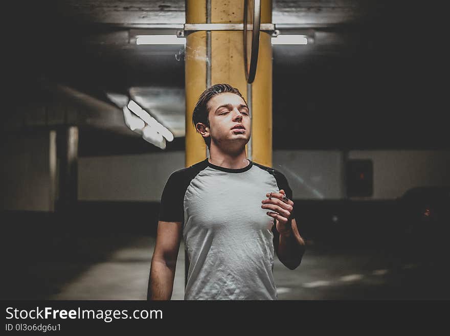 Man Wearing Gray and Black Raglan T-shirt Standing Near Orange Post