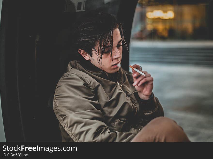 Man Wearing Gray Jacket Holding Cigarette