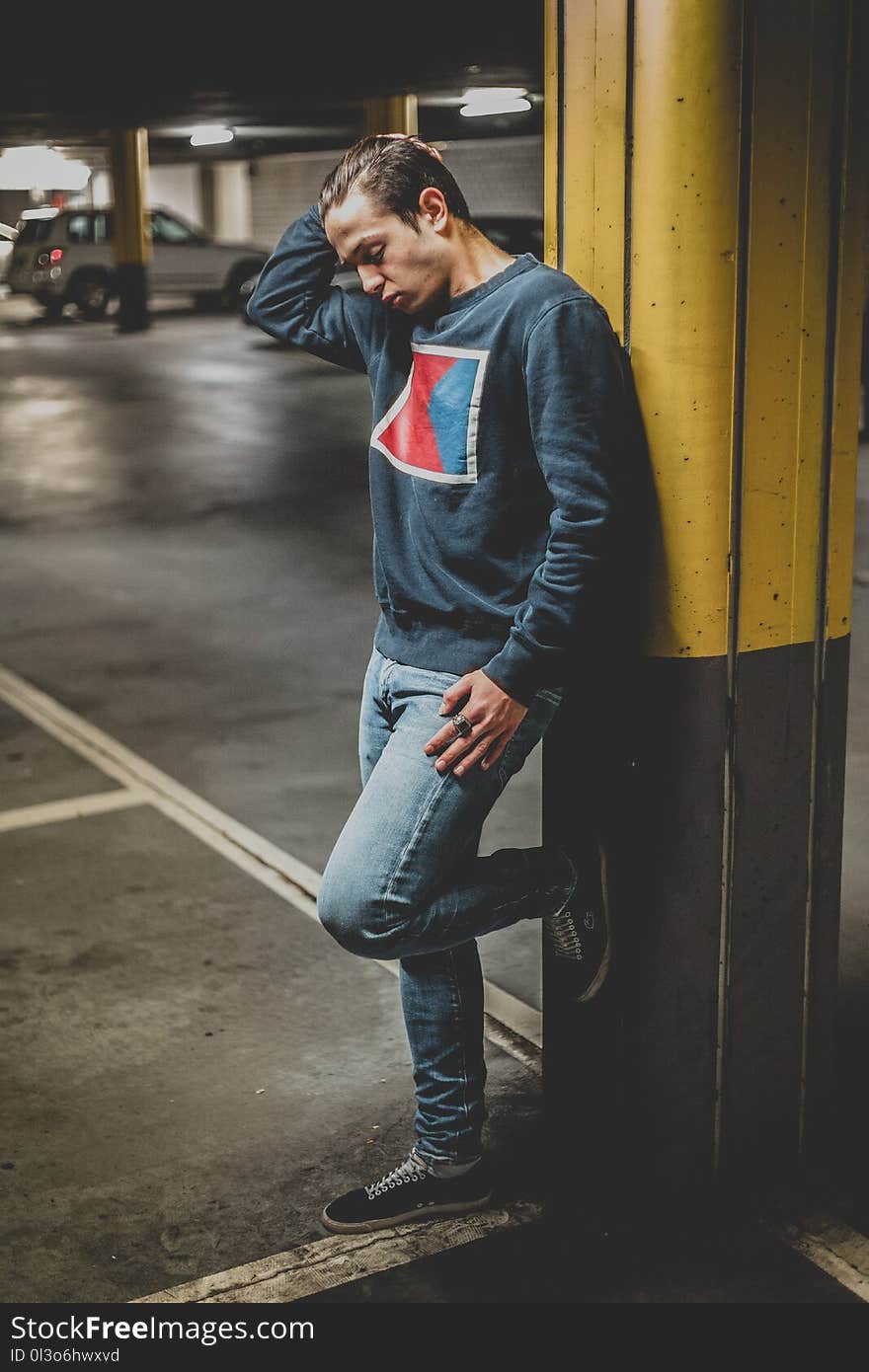 Man Leaning on Yellow and Gray Metal Post