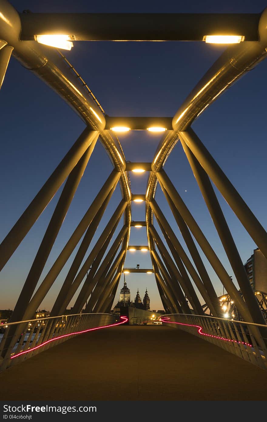 Two red light trails from two bicycles on a modern bridge at dusk