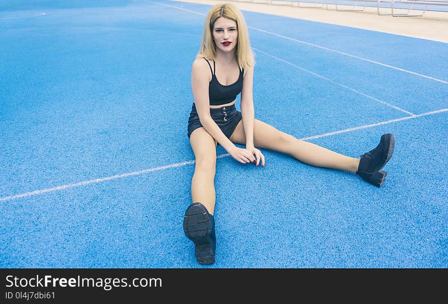 Woman Wearing Black Sports Bra and Black Shorts Sitting on Ground