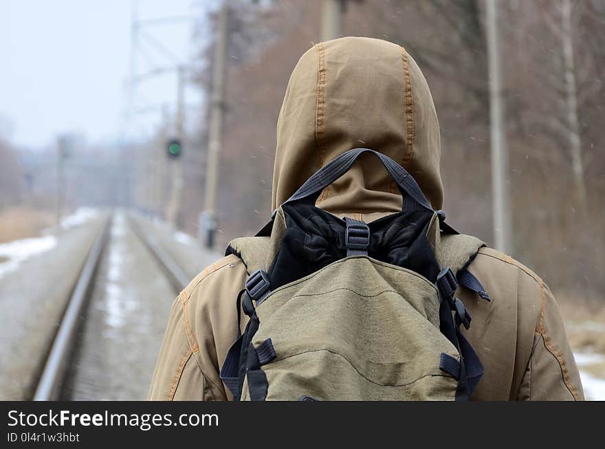 A man with a large backpack goes ahead on the railway track during the winter season .