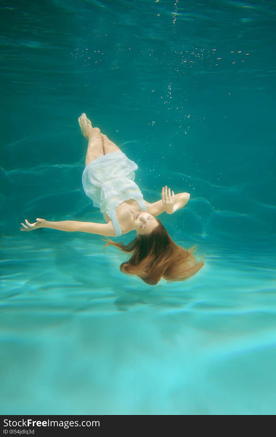 Underwater scene. Girl mermaid with healthy shiny beautiful long hair. A woman, a fashion model in the water in a beautiful dress swims like a fish.