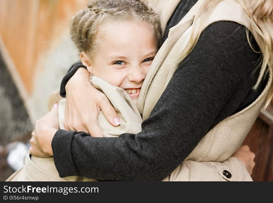 Happy Girl 7 Years With Blonde Hair Laughing And Hugging With Mom