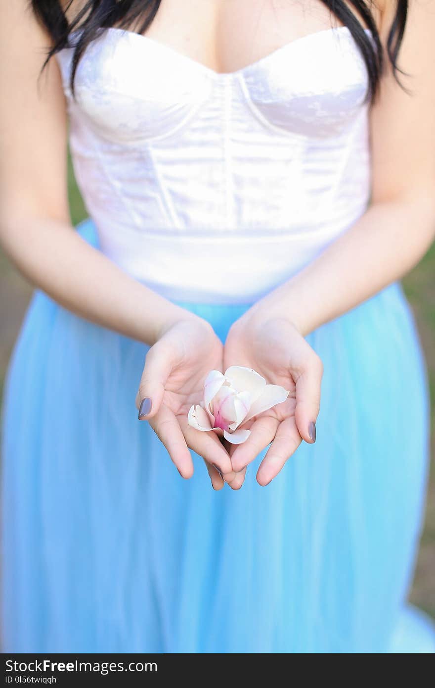 Brunette woman keeping magnolia flower in hands. Concept of beauty and nature.